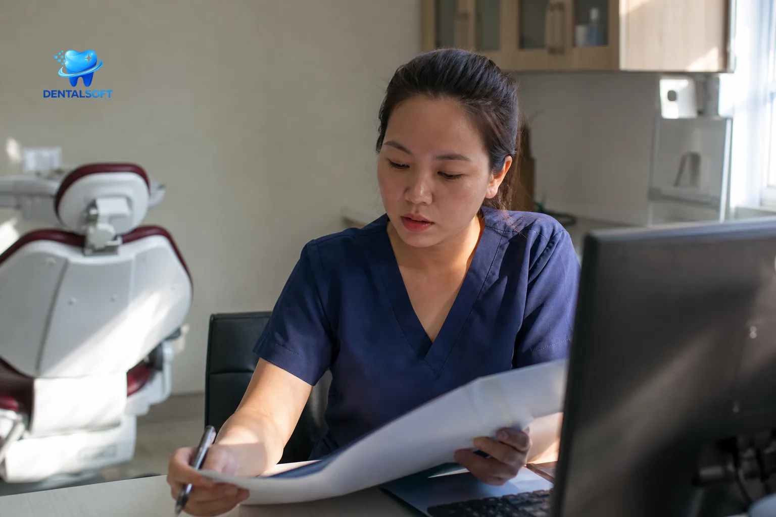 Nhân viên nha khoa đang đối chiếu hồ sơ bệnh nhân với máy tính trong phòng khám